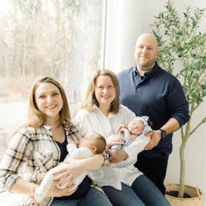 a couple with their surrogate mother, holding two babies
