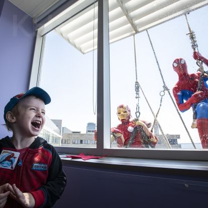 a young boy is thrilled to be visited by iron man and spiderman
