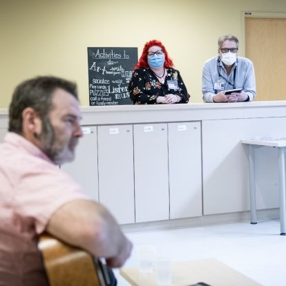 Staff watch a guitarist performing for patients.