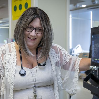 Kim standing next to an ultrasound monitor, speaking with a patient