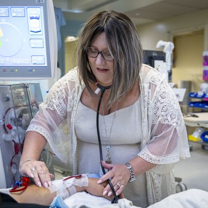 Kim standing next to a patient, examining their arm