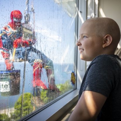 a young patient watches spiderman washing windows at KHSC