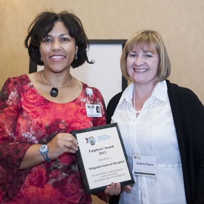 Micki Muima, Director of Healthy Workplace Services (left) accepts the Employer Award 2013 from Andrea Payne of the Kingston Immigration Partnership at the Residence Inn Mariott.