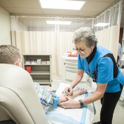 Phlebotomist Deb Webster at work in one of the stations in the relocated Blood Room in the Burr wing lobby.