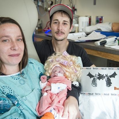 Mom and Dad with their new baby who is dressed up for Halloween