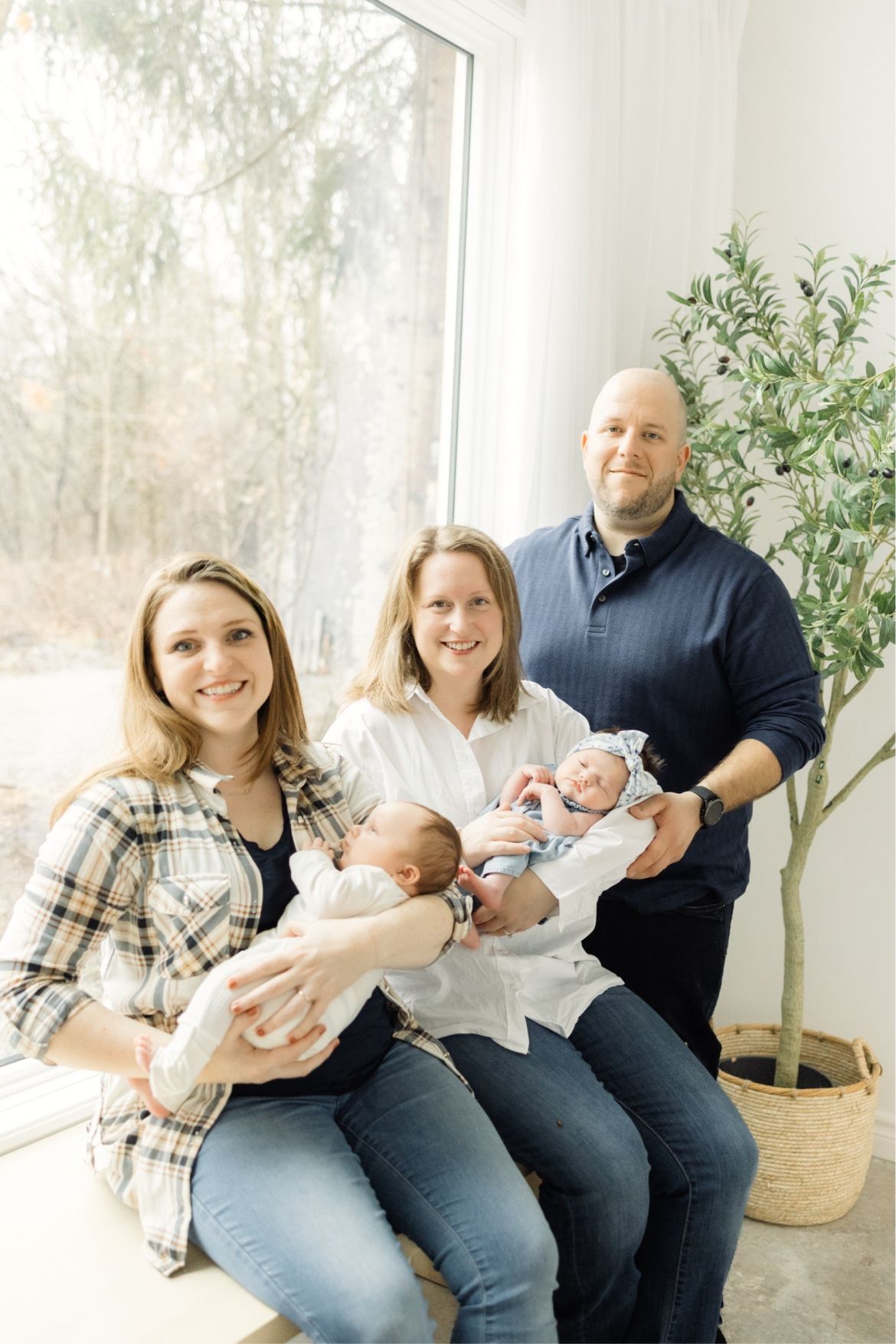 a couple with their surrogate mother, holding two babies