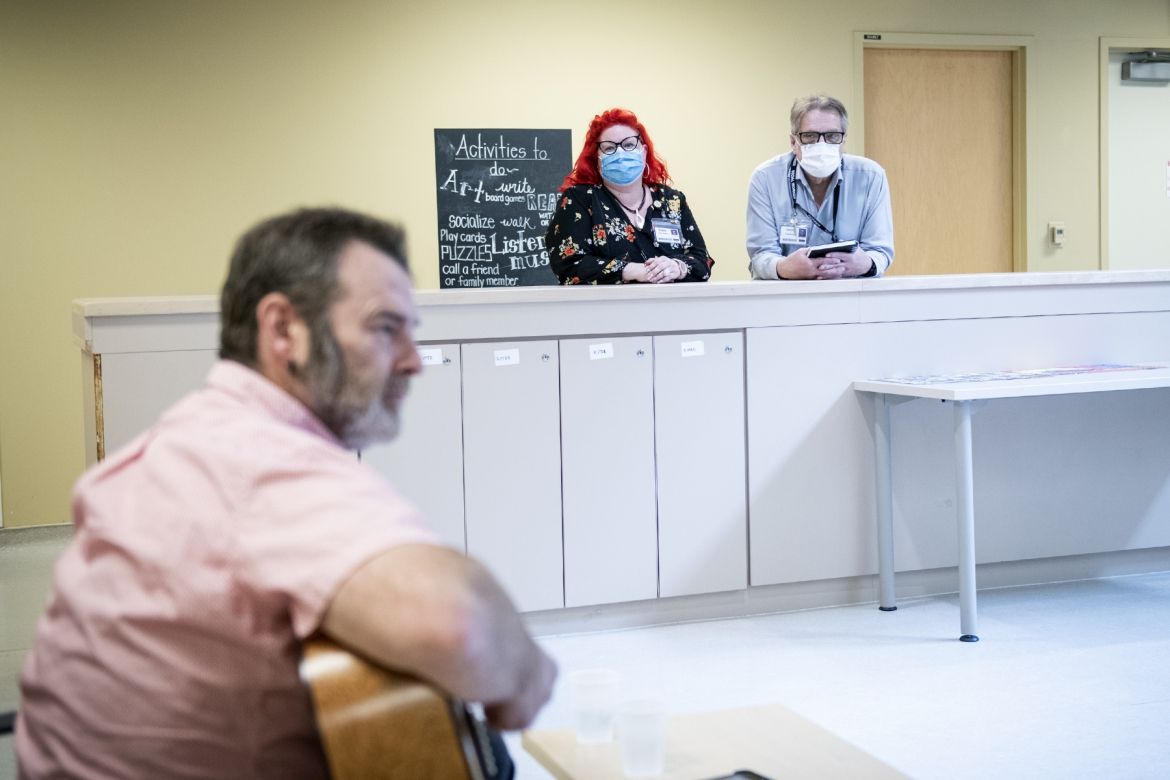 Staff watch a guitarist performing for patients.