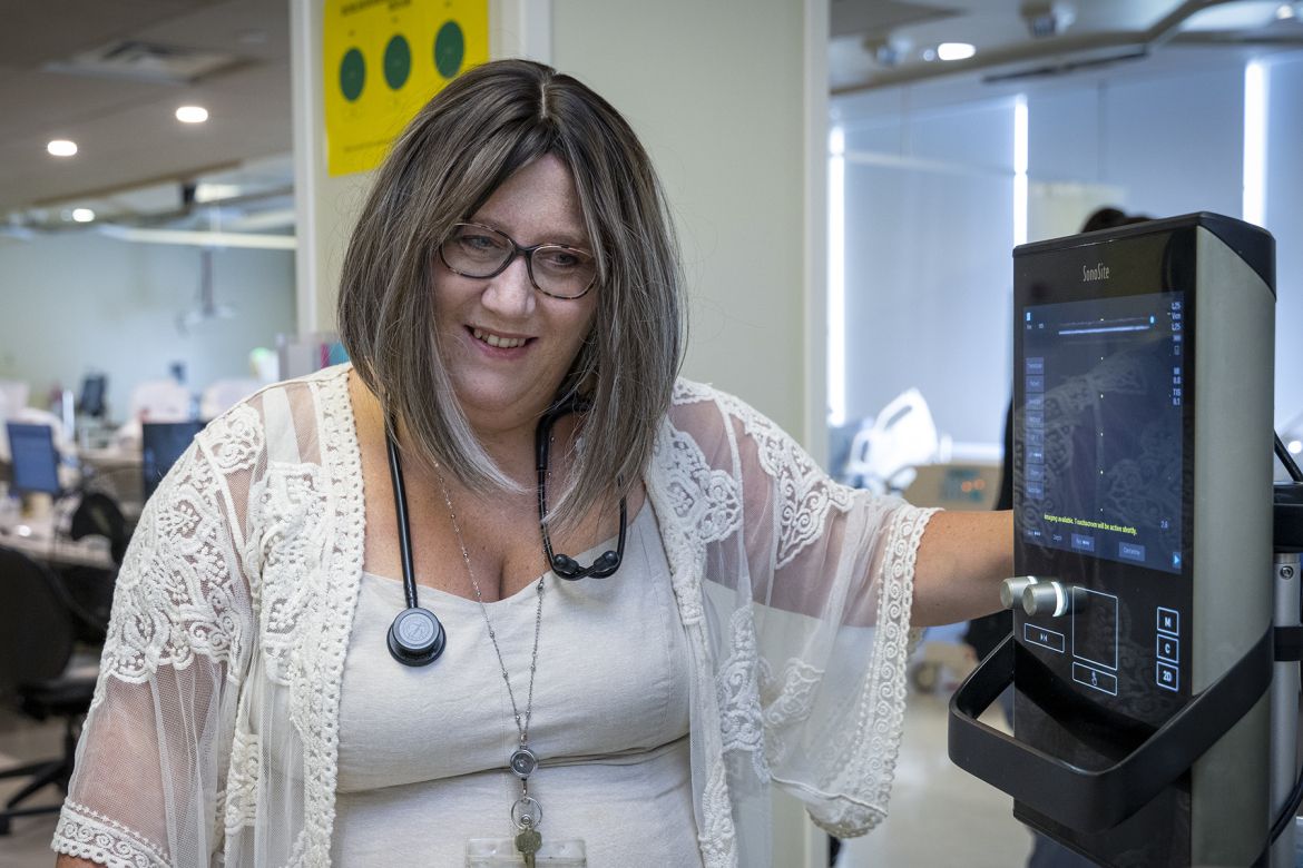 Kim standing next to an ultrasound monitor, speaking with a patient