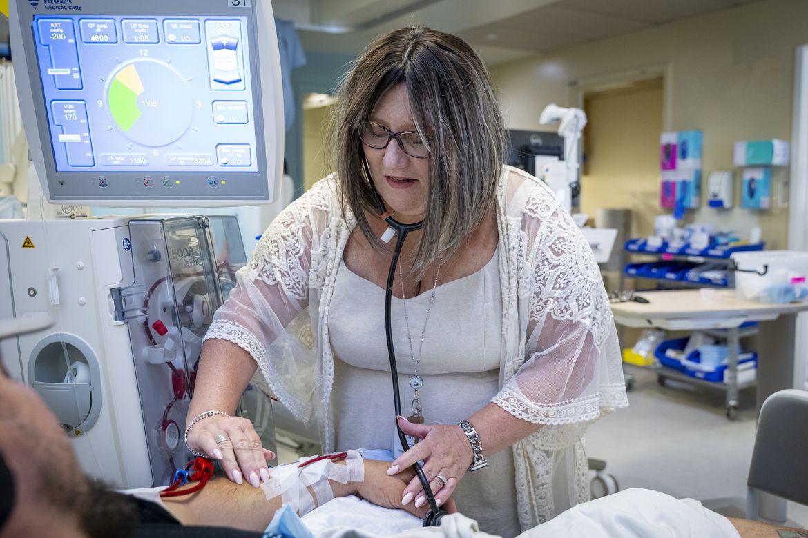 Kim standing next to a patient, examining their arm
