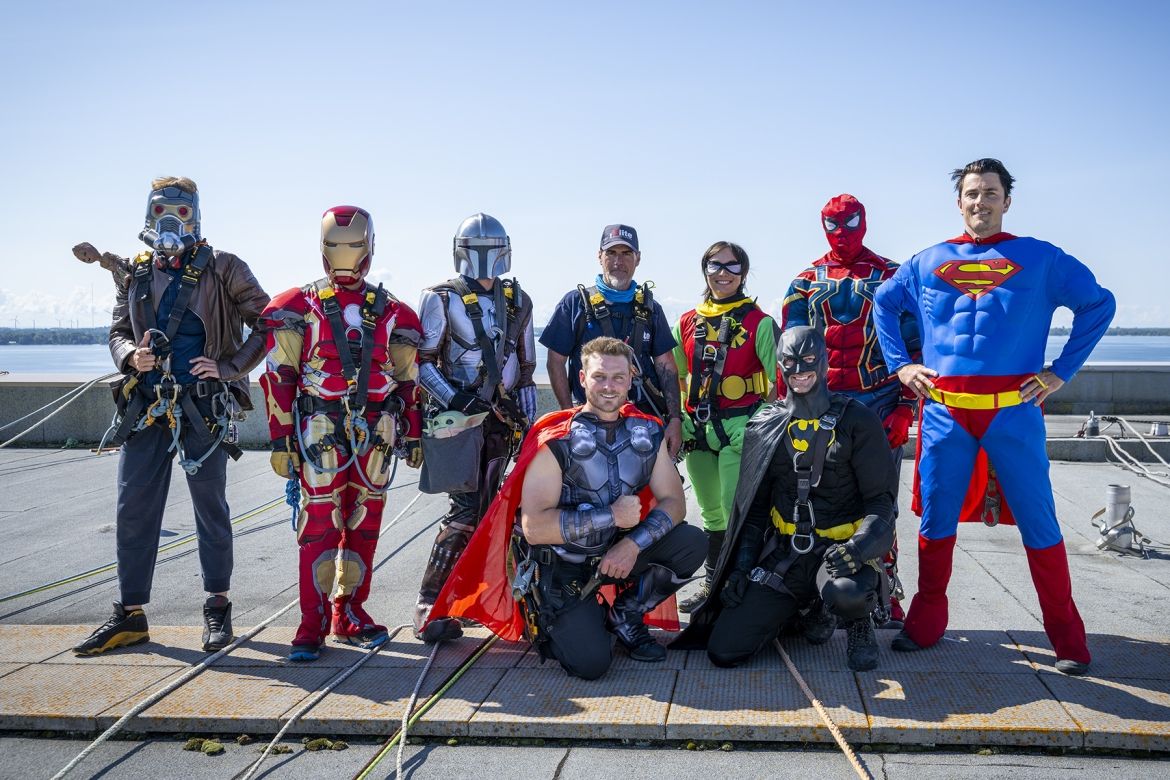 a group of superheroes stand on the roof of Kingston General Hospital