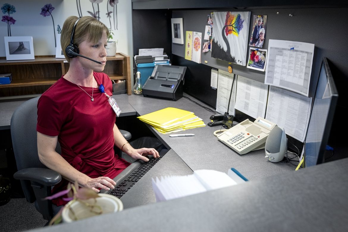 People of KHSC - Taryn Oegema Taryn Oegema is pictured sitting at her desk, looking at her computer. She has a headset on and her fingers are typing on her keyboard. She has short blonde hair, blue eyes and is wearing a dark red dress.