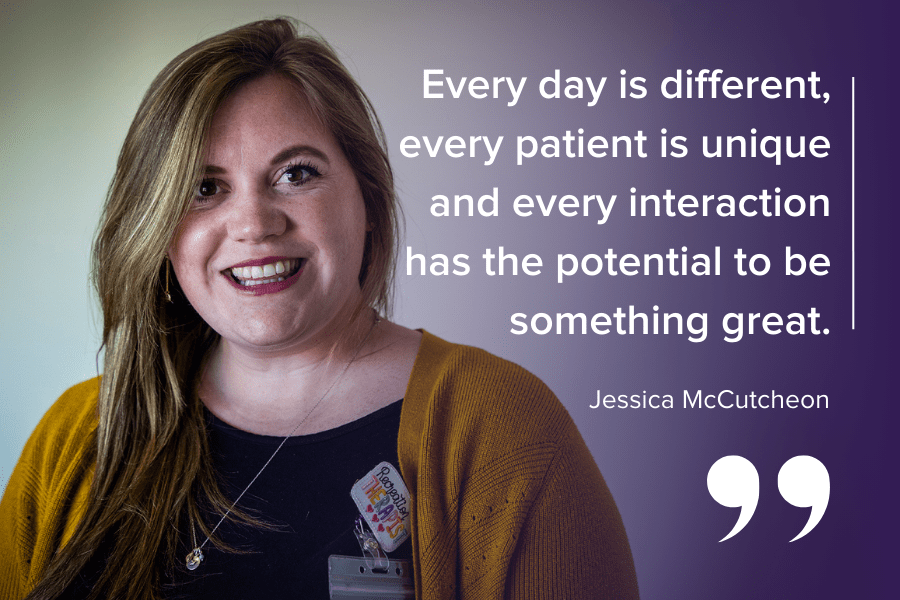 Jessica McCutcheon is pictured looking directly into the camera and smiling. McCutcheon has dark blonde hair and brown eyes. She’s wearing a black top, mustard cardigan and a badge that says recreation therapist stitched in rainbow colours.