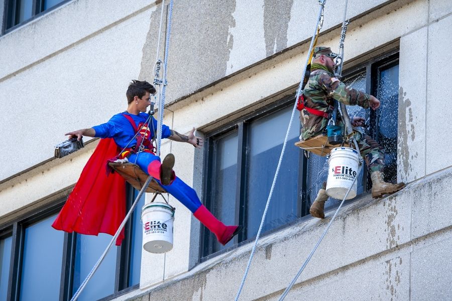 Dennis Clark is pictured hanging off the side of the KGH building with window washing equipment, dressed as Superman.
