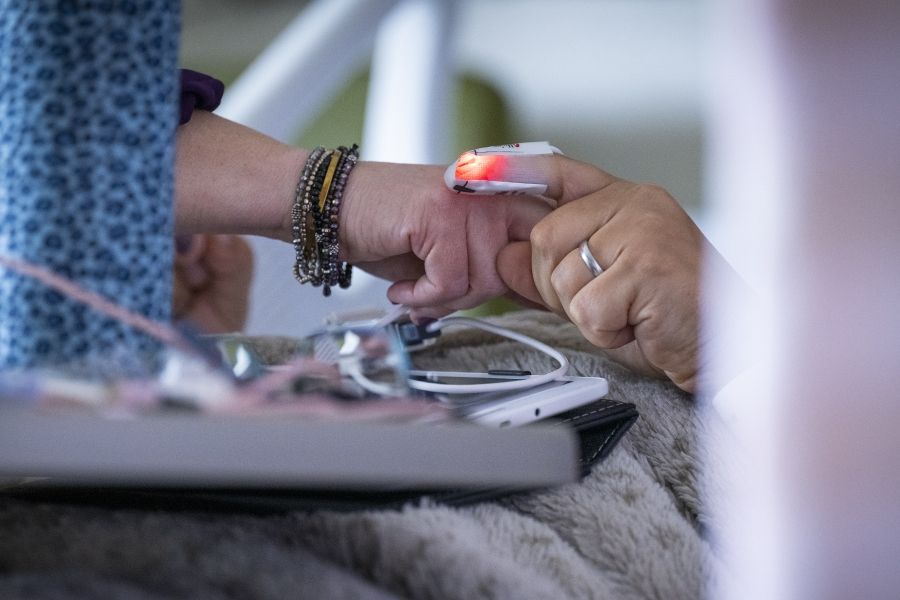 A close up shot of Melissa Meisner holding hands with a patient, who is being monitored in the EMU.