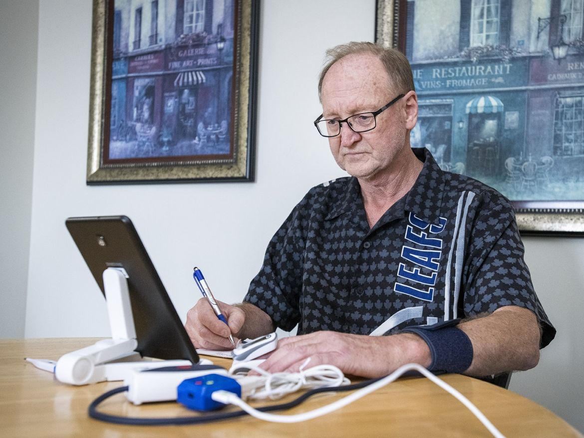 Patient Herbert Rae at home using remote monitoring technology to record vital signs.