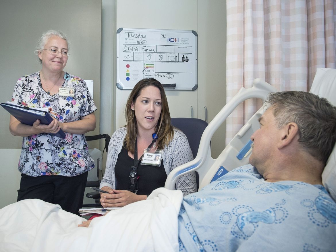patient care with staff talking to a patient in a bed
