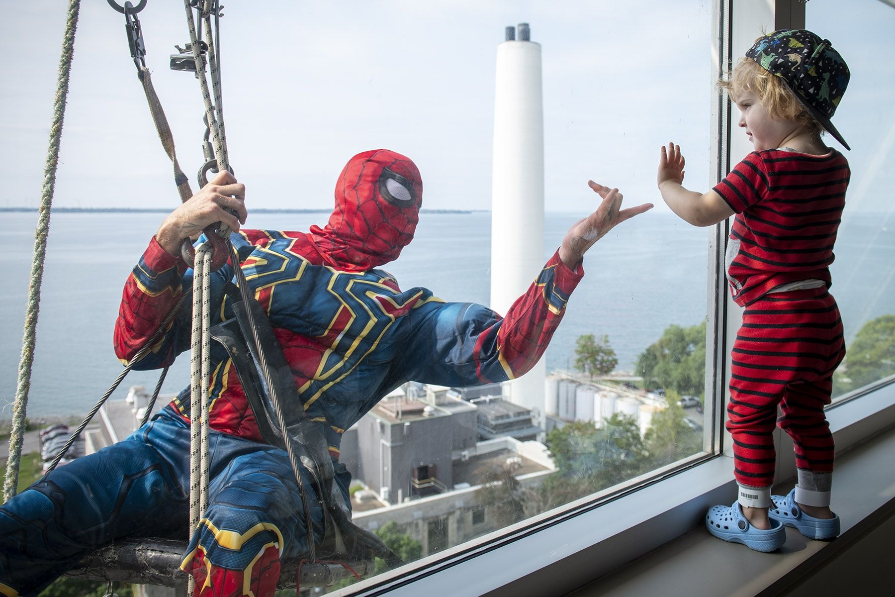 Image of Spiderman window washer with child at window