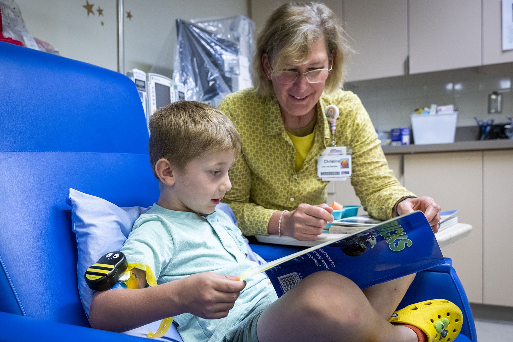 Child Life staff reading a book to a young patient 