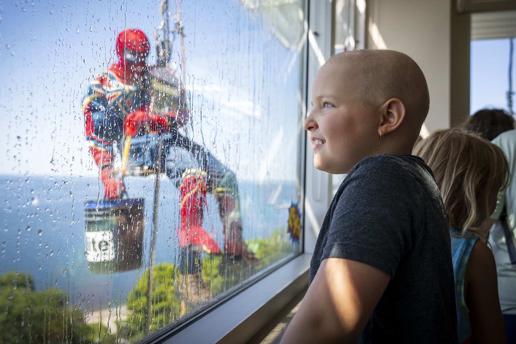 a young patient watches spiderman washing windows at KHSC 