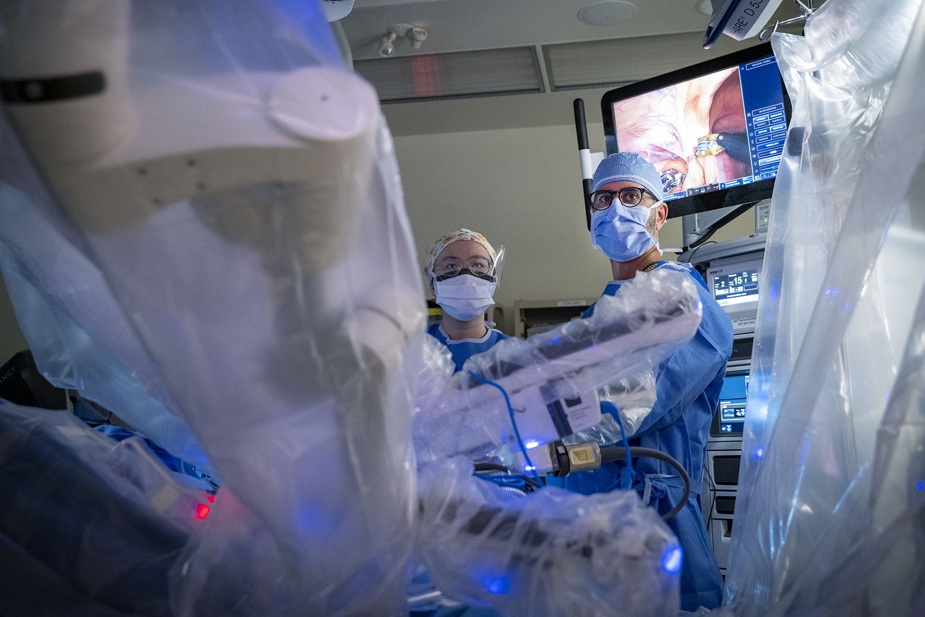 Dr. Sunil Patel and a student are standing behind the Davinci robot during surgery.