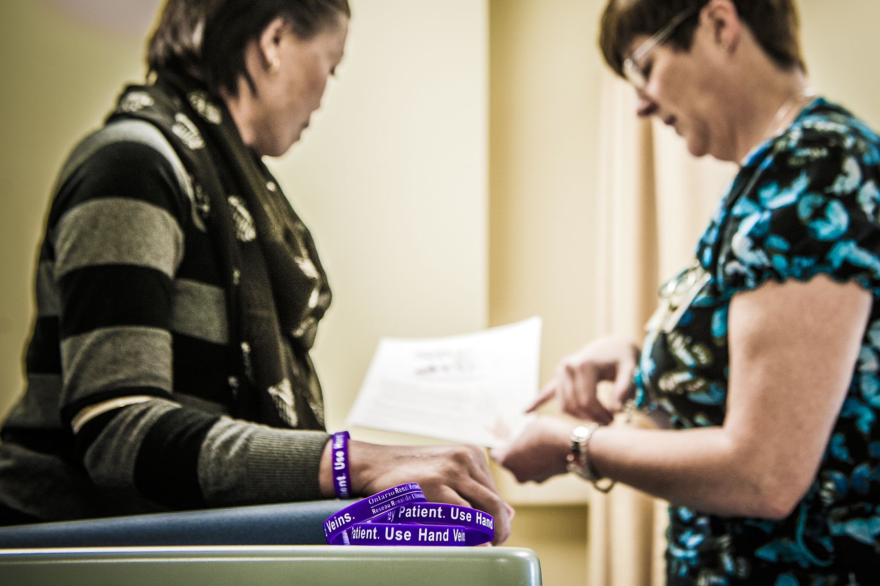 Registered Nurse Andrea Knapp (right) draws blood from the hand of renal patient Cecilia Tran.