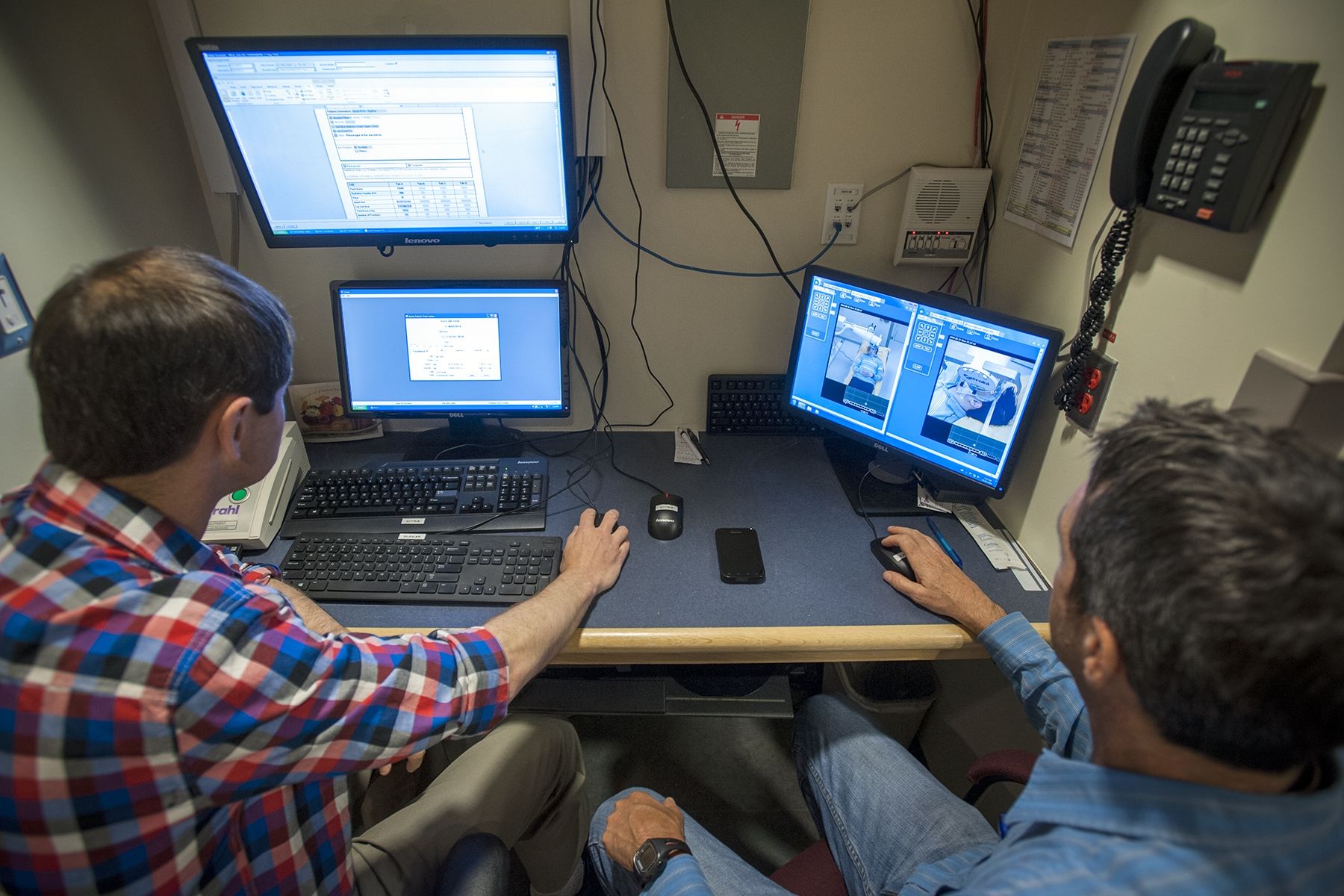 Radiation Therapists Jim Gooding (left) and David Markotich demonstrate how orthovoltage treatment is given to a patient.