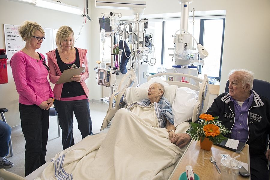 (From left) RNs Amber Elliot and Amy Kirst do a standardized bedside handover with patient Beverly Philips and her husband Charles