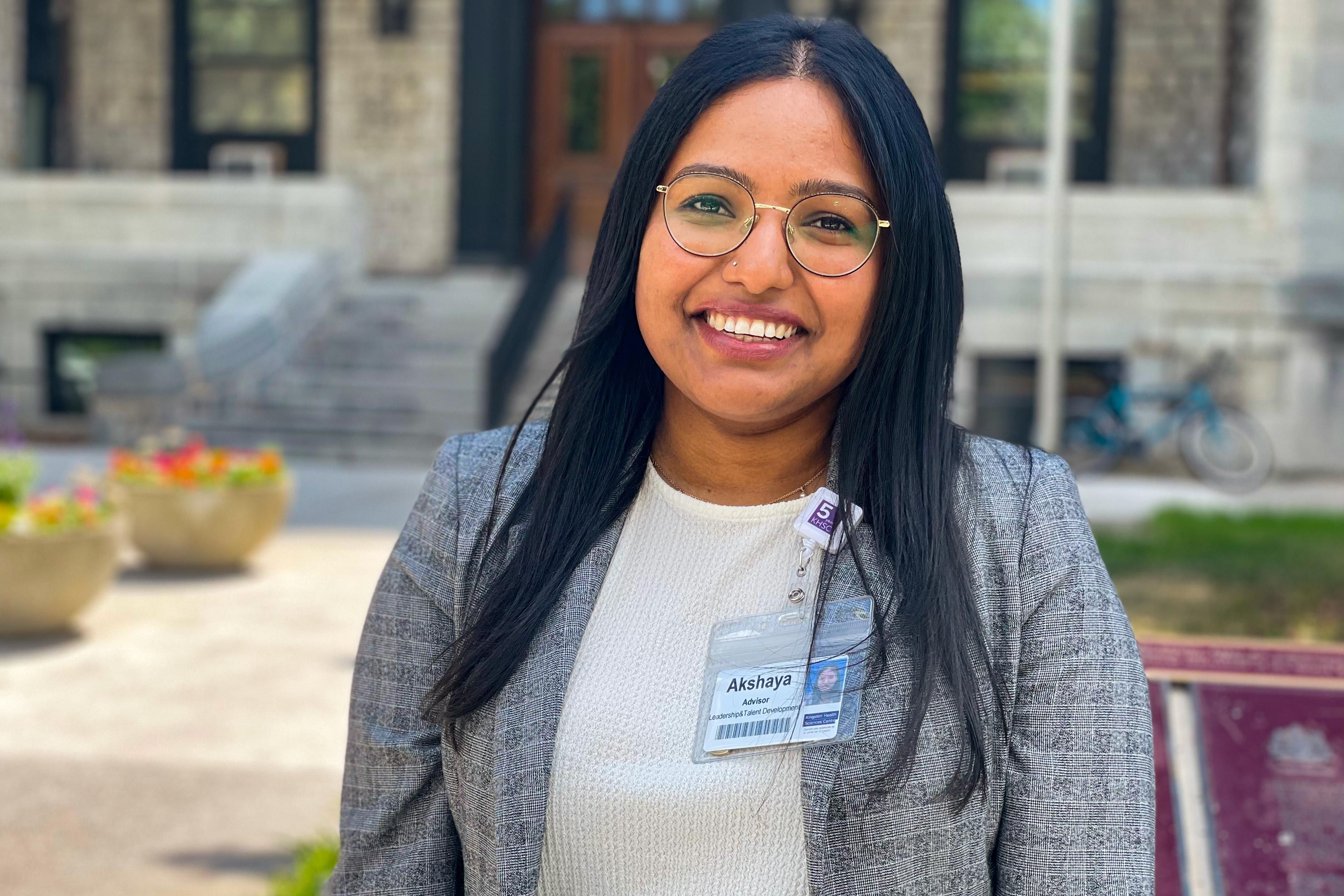 A mid shot image of Akshaya Arun who has shoulder length black hair and brown eyes, and is wearing a grey blazer and white top.