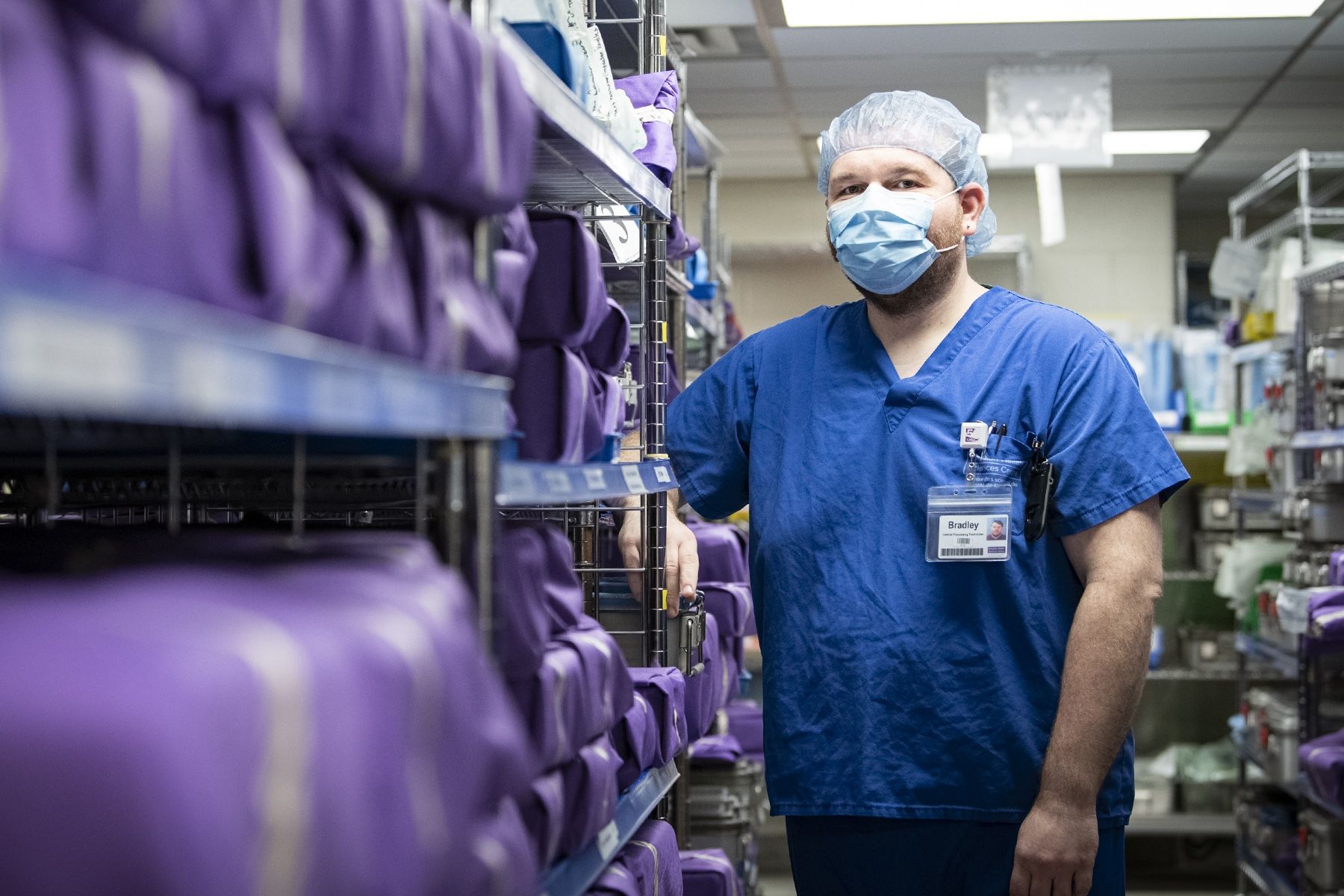 Bradley Leaver is wearing blue scrubs and photographed inside the Medical Device Reprocessing department at KHSC.