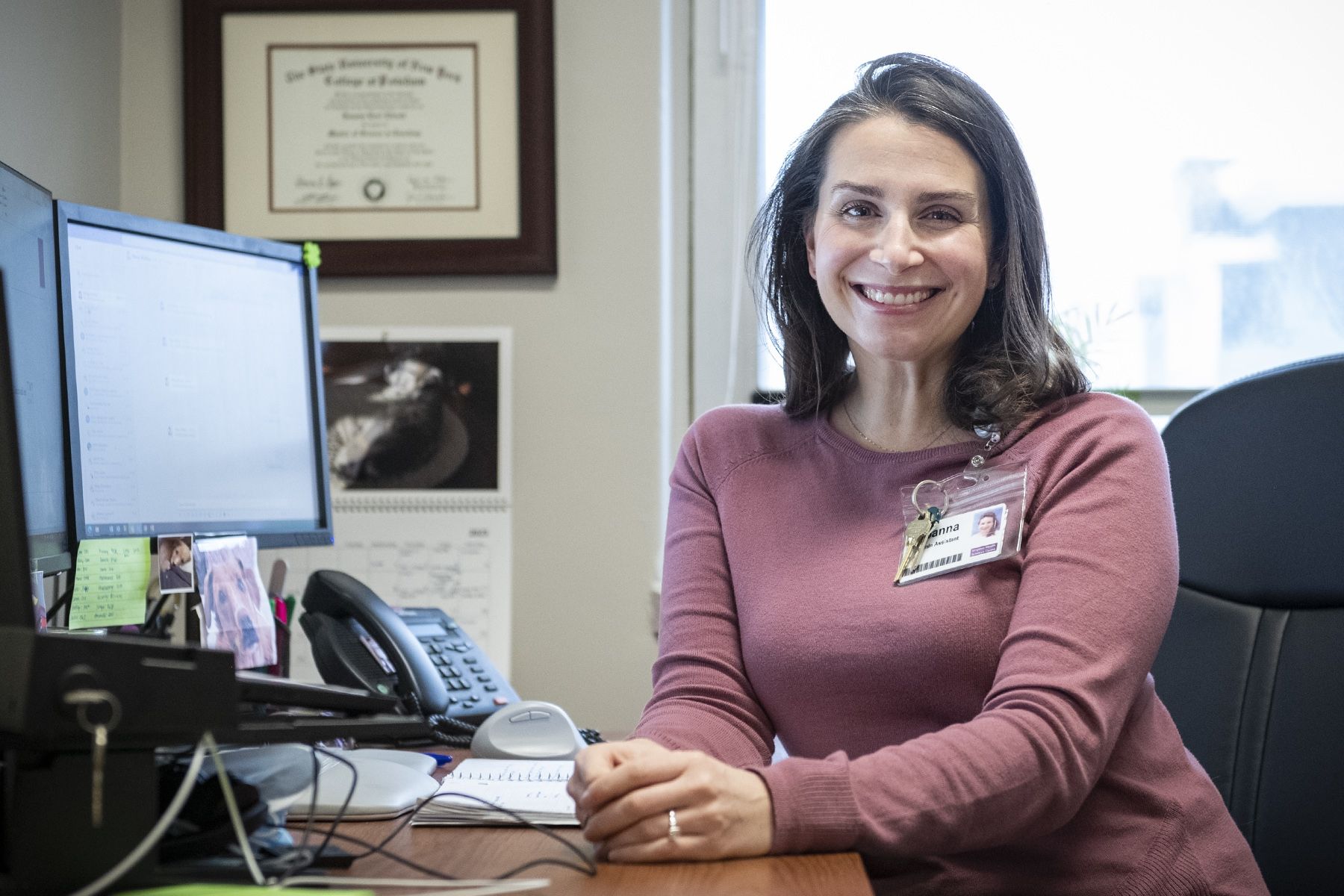 Joanna Elliott is pictured sitting at her desk at the Hotel Dieu Hospital site. She has shoulder length, dark brown hair and is wearing a mauve blouse.