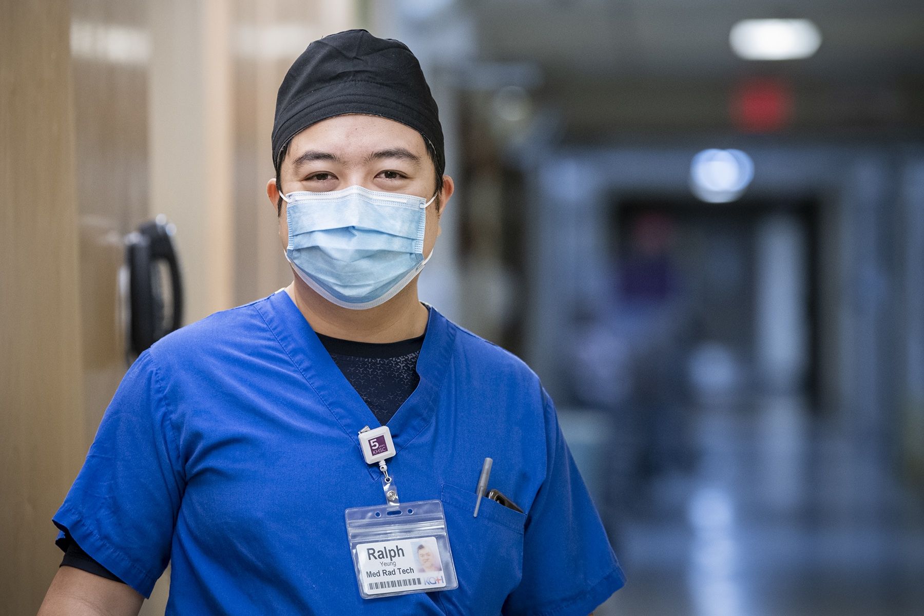 Ralph Yeung is pictured in a hallway at the KGH site. He's wearing blue scrubs, a mask and black scrub hat.